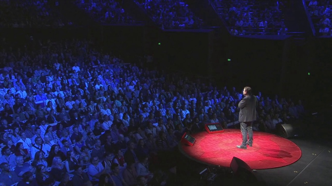 Person speaking on a stage in front of a large audience